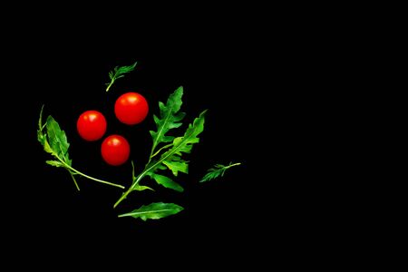 Cherry tomatoes with rukola leaves isolated on blackの写真素材