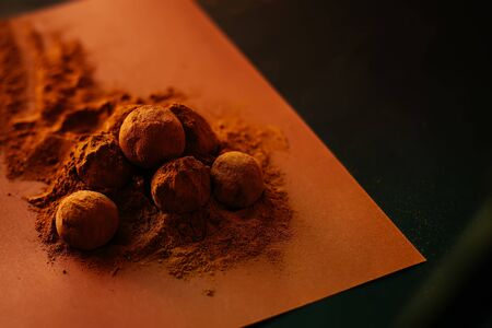 Chocolate balls with cocoa powder spread over brown backgroundの写真素材