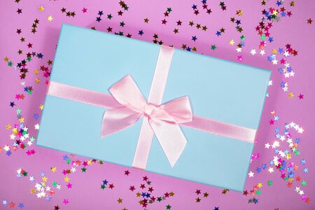 Beautiful gift box with atlas ribbon on purple background with sparkling stars, festive conceptの写真素材