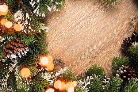 Christmas tree branch wreath with blue and green baubles and golden defocused lights on wooden backgroundの写真素材