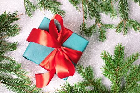 Bright christmas gift with colorful atlas ribbon and christmas tree branches on white backgroundの写真素材