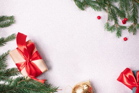 Bright christmas gift with colorful atlas ribbon and christmas tree branches and red berries on white silver shimmer backgroundの写真素材
