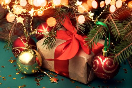 Christmas gift with atlas ribbon under the tree with baubles asideの写真素材