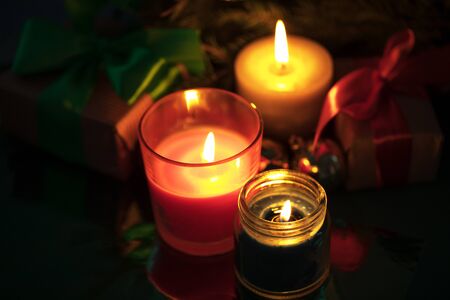 Festive christmas burning candles under the tree with gift boxesの写真素材