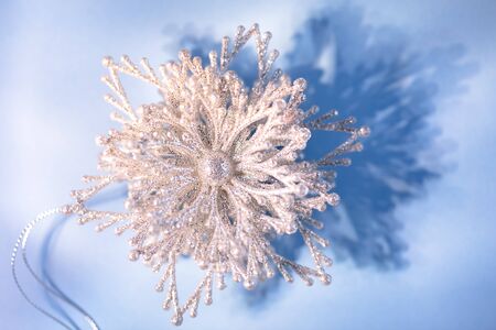 Silver sparkling snow flake on blue background close up, festive conceptの写真素材