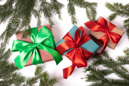 Bright christmas gifts with colorful atlas ribbon and christmas tree branches on white backgroundの写真素材
