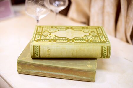 Old fashioned books on table with wine blurred wine glasses behind glassの写真素材