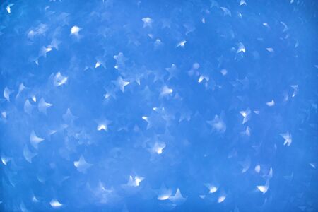 Sparkling stars blurred bokeh blue background, winter, christmasの写真素材