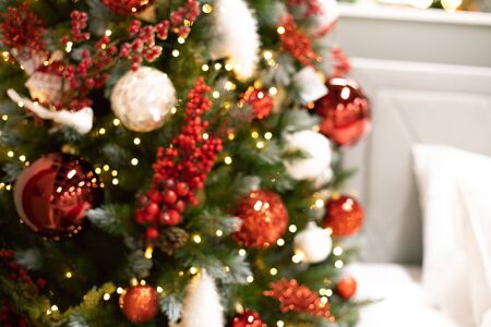 Blurred picture of christmas tree with led lights bokeh, baubles, balls, toys, holy berries on fir branchesの写真素材