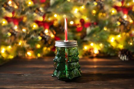Festive christmas background, christmad tree bevarage bottle on wooden table with colorful bokeh led lightsの写真素材