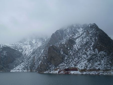 Lazy river flows past the foot of a large snow covered mountain peak.の写真素材