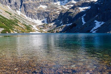 Clear water of mountains lake. Snowy rocksの写真素材