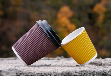 A pair of brown yellow paper cups, take out, coffee to go. Two eco-friendly heat proof cardboard mugs, close up. Concept of addiction, friendship, support, relations, male femaleの写真素材