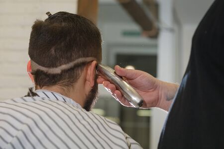 Close up shot: Barber working with hair clipper. Hipster client getting haircut. Haircut, styling concept.の写真素材