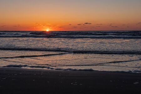 Beautiful sunset landscape at the North sea and orange sky with awesome sun golden reflection on waves as a background. Amazing summer sunset view on the beach.の写真素材