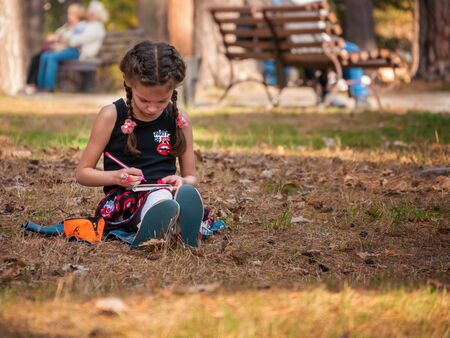 Cute caucasian little girl 6 years painting in the autumn park, concept outdoors painter talented alone kids education in natureの写真素材