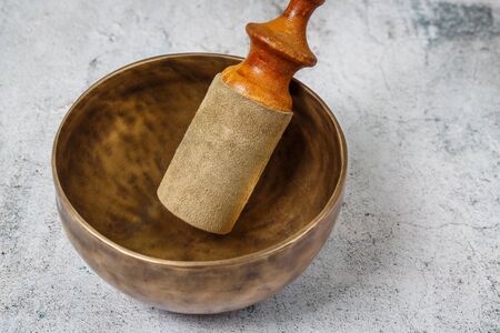 Tibetian old metal singing bowl with stick standing on the concrete background. Health, healing and meditation conceptの写真素材