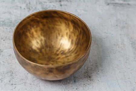 Tibetian old metal singing bowl standing on the concrete background. Health, healing and meditation conceptの写真素材