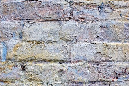 Part of an old brick wall is covered with old plaster. Shabby building facade with damaged plaster. Grunge stone wall background texture and place for textの写真素材