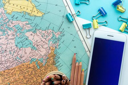 Desktop design with map of Canada, colorful paperclips, colored pencils and mobile phone