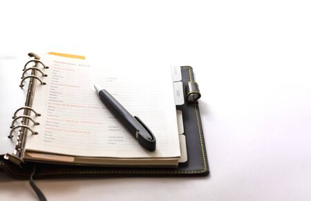 White paper ring organizer book open on the white background with a black pen