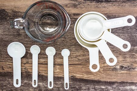 Set of white measuring cups, measuring spoons and  measuring glass use in cooking lay on wooden tabletop in in top viewの写真素材