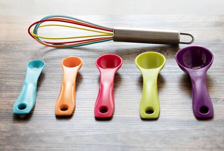 Set of measuring spoons and silicone whisk use in cooking lay on wooden tabletop in top viewの写真素材