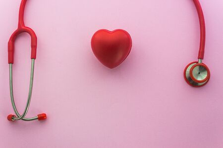 Red stethoscope and the heart on pink background with copy space
