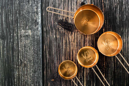 Collection of bronze measuring cups on old wood table background in top viewの写真素材