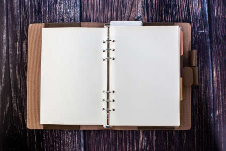 An open blank planner, spiral binders with leather cover and colorful tabs index, isolated on wood table.の写真素材
