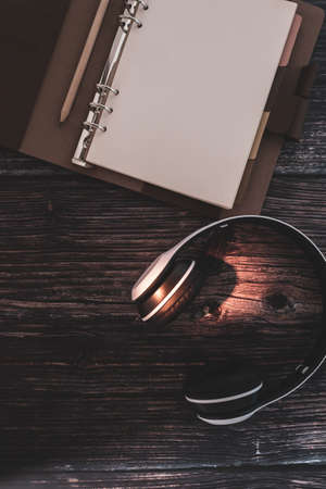 Podcast content planning concept. Blank page ring planner with headphone on dark brown wooden desktopの写真素材