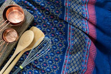 Kitchen utensils concept, measuring cups with whisk and wooden spoon on traditional cloth backgroundの写真素材
