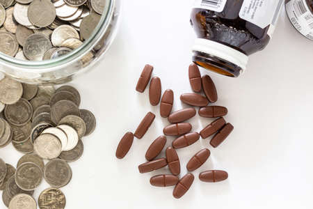 Drugs and coins on white background. Healthcare cost grow too high in every year so people have to plan a budget for support their expense.の写真素材