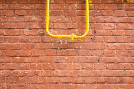 old red brick wall background. brick wall texture. grunge wallpaper. yellow pipeの写真素材