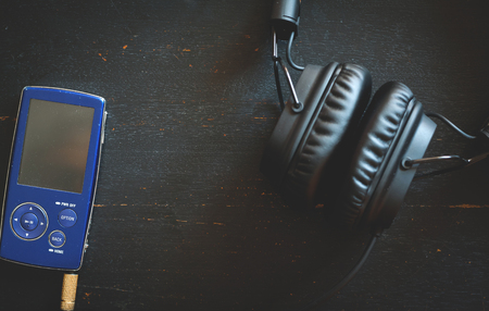 Pocket music player with vintage headphones on black wooden background