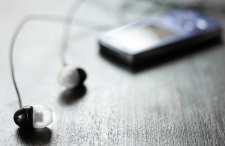 Pocket music player with in-ear headphones on black wooden backgroundの写真素材