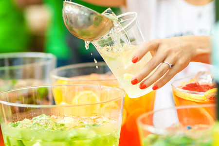 Woman pours lemonade into a glass with a scoop. Family picnic.の写真素材