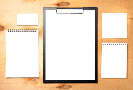 Blank clipboard, business card and notepads on wooden background. Business essentials.の写真素材