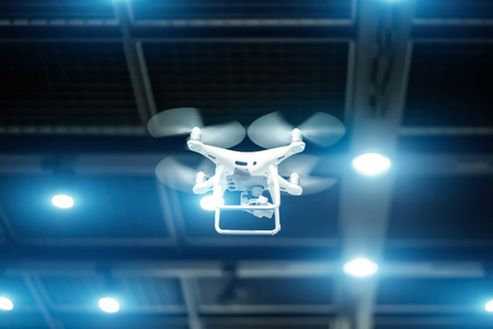 White drone in motion. Quadcopter flying inside a large warehouseの写真素材