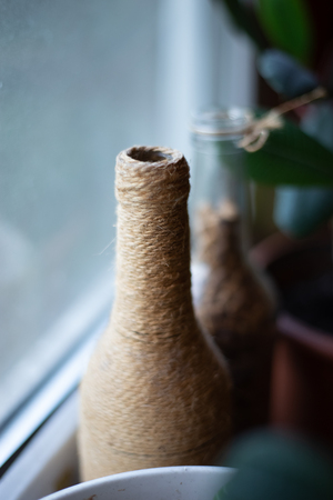 Bottle decorated with twine in low light.の写真素材