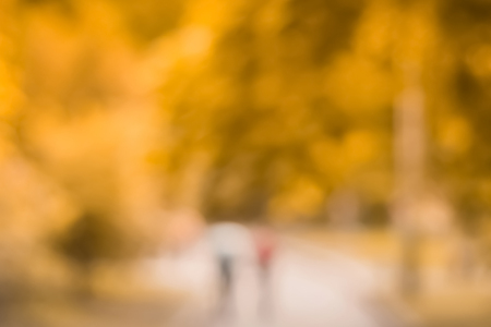 Blurry autumn park background. Forest bokeh. People walk in the parkの写真素材