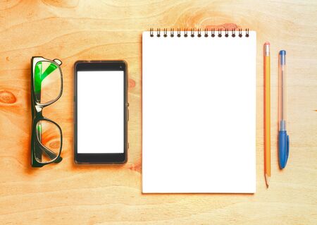Business essentials. Top view of spiral blank notebook and smartphone on wood desk backgroundの写真素材