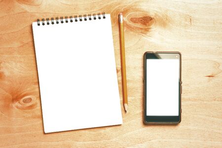Business essentials. Top view of spiral blank notebook and pencil on wood desk backgroundの写真素材