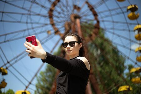 Girl taking selfie in Pripyat amusement park on the ferris wheel backgroundの写真素材