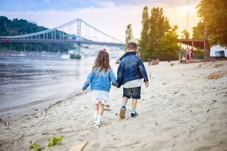 Two children walking along the beach at sunsetの写真素材