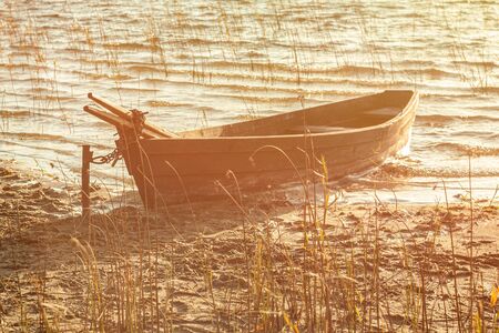 Old wooden boat moored on the mudy shore lakeの写真素材