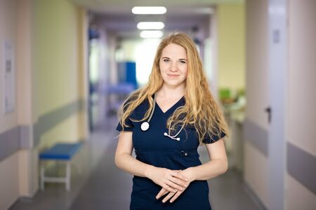 Smiling nurse with stethoscope in hospital hallwayの写真素材