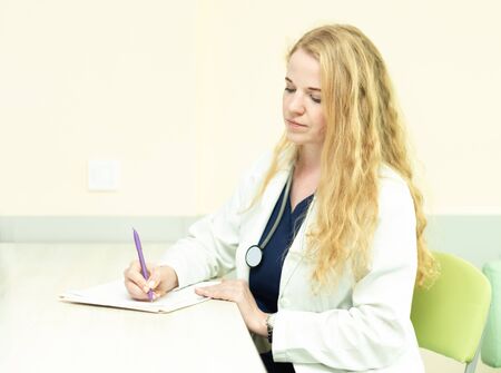 Medical doctor with a stethoscope takes notesの写真素材