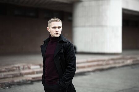 Serious man in black trenchcoat and purple polo neckの写真素材