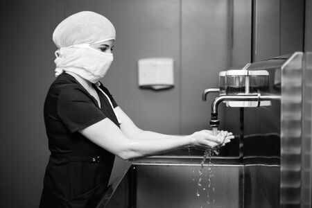 Nurse in protective medical mask washes handsの写真素材